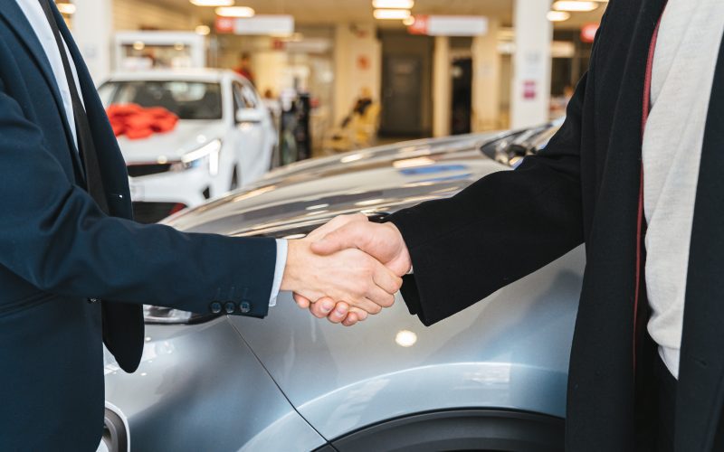 Graphic illustrating auto financing with bad credit, featuring a person with a concerned expression reviewing financial documents, a credit report with a low score, and a car dealer handing over car keys.