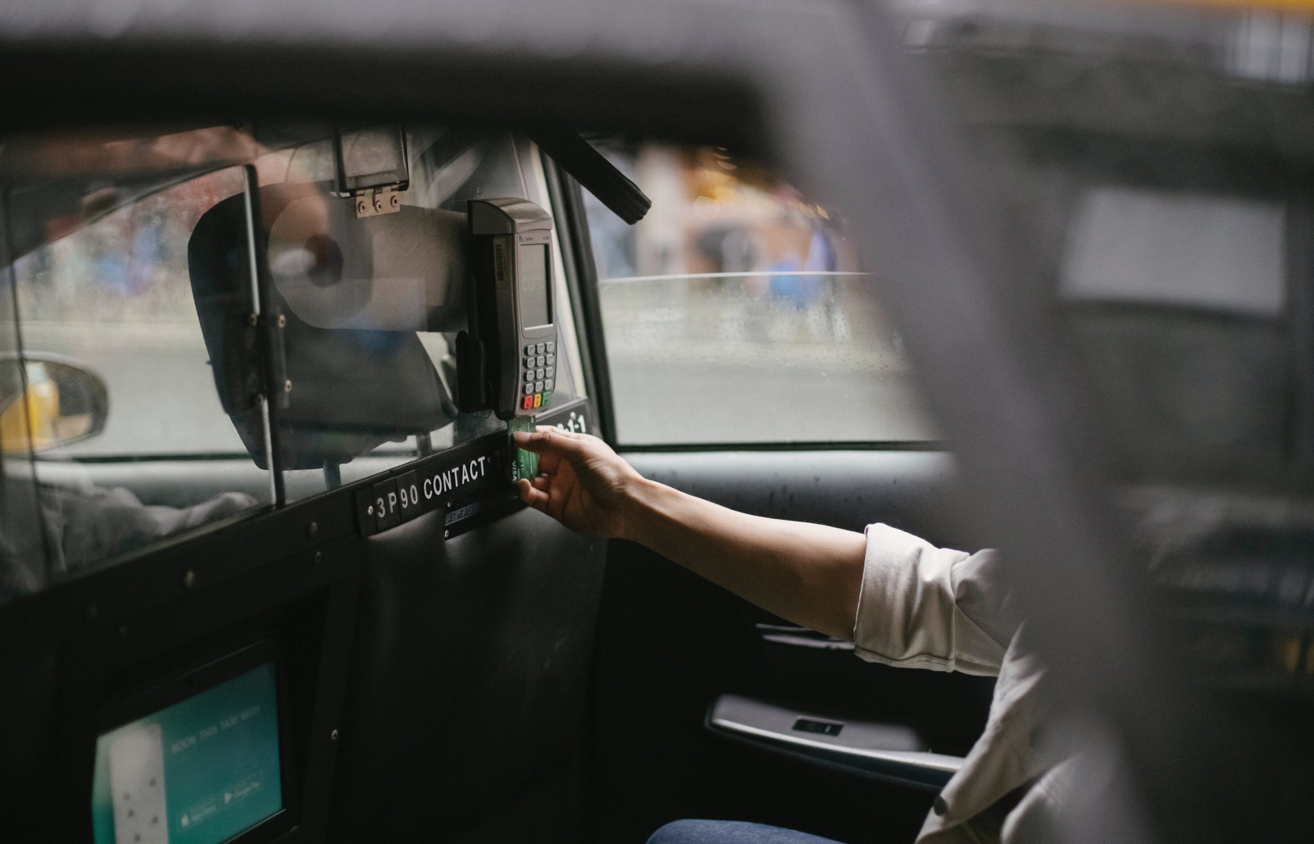 A finance manager at a car dealership discussing loan terms with a customer who has bad credit. Papers and a calculator are on the desk, with car loan posters in the background.