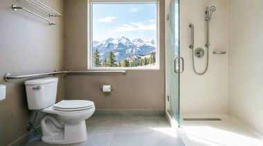 Modern accessible bathroom with stainless steel grab bars near toilet and walk-in shower, featuring scenic Colorado Rocky Mountain view through window, professional home safety modification for seniors aging in place